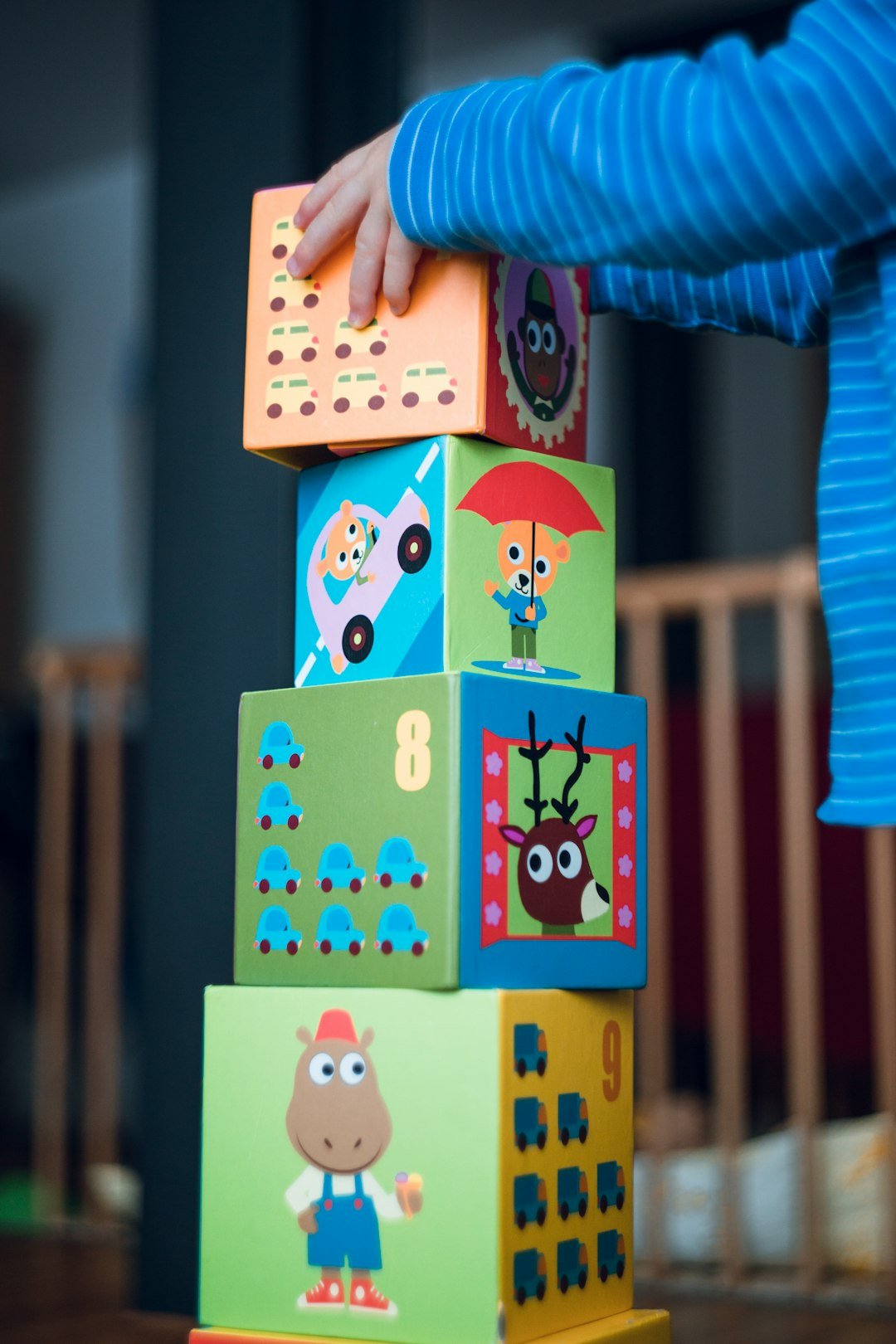 Young boy stacks funny animal comic cardboard boxes. Early childhood motor skills.